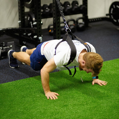 Man doing a push-up in the PUSH Perfect vest with the cord clipped to a gym rack