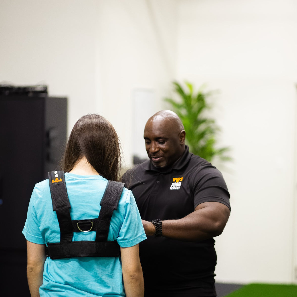 Back view of the PUSH Perfect vest while a trainer checks the fit